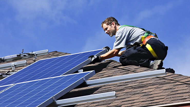 Installation de panneaux solaires sur le toit d'une maison.